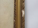an old picture of a gold frame with a white wall in the background