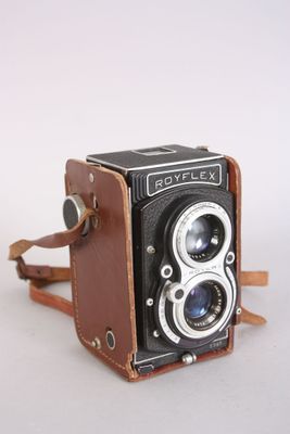 an old camera with a leather case and strap on a white surface