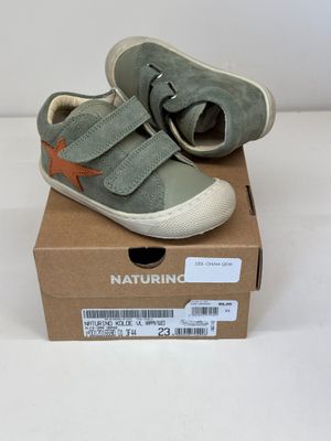 des chaussures de petit garçon dans une boîte posée sur une surface blanche
