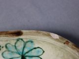 a close up of a plate with a flower painted on it