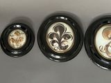 four oval picture frames mounted on a wall with a fleur de lis design