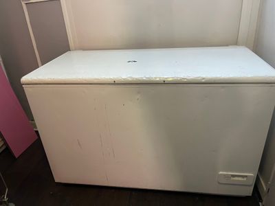 a white chest freezer sitting in the corner of a room