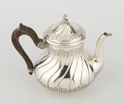 a silver teapot with a wooden handle on a white surface