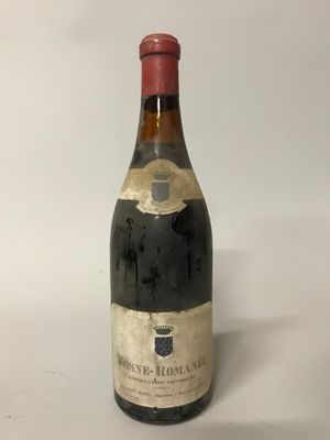 une vieille bouteille de vin posée sur une table blanche