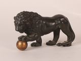 statue en bronze représentant un lion tenant une boule dorée entre ses pattes