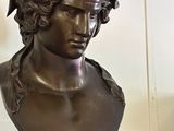 a bronze bust of a man with a bird on his head