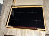a black stove top with a wooden frame on a table