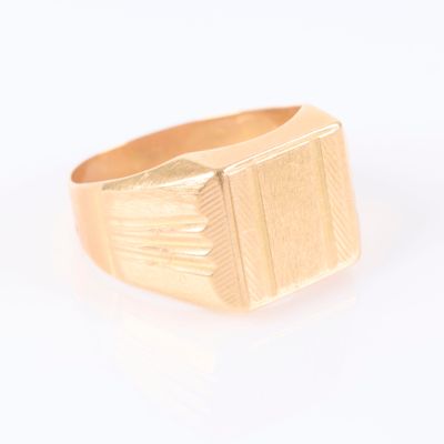 une image d'un gros plan d'une bague en or sur une surface blanche