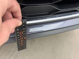 someone is measuring the width of a car ' s bumper with a ruler