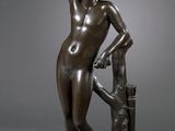 an image of a bronze statue of a woman standing next to a tree
