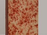 an old book with red spots on it sitting on a white surface