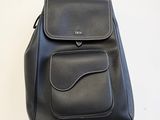sac à dos en cuir noir à roulettes posé sur une surface blanche, sur fond blanc