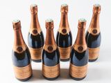 six bottles of champagne are lined up on a white surface