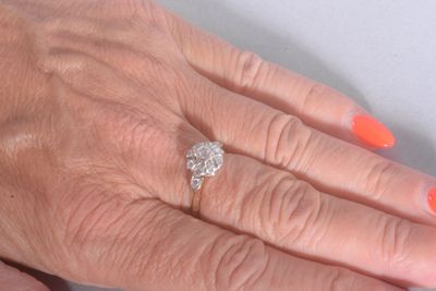 a woman ' s hand with a diamond ring on it