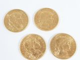 four gold sovereigns on a white surface with a white background