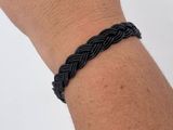 a black braided bracelet on a person ' s arm
