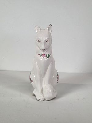 a white cat sitting on the floor with a flower on it ' s collar