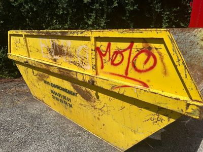 une benne jaune avec des graffitis sur le côté