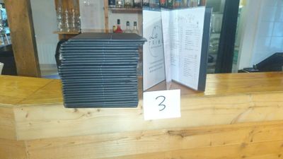 a picture of a restaurant counter with a menu and wine glasses on it