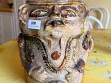 un vase orné d'un visage, posé sur une table