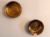 two gold plates on the wall next to each other