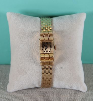 an image of a gold wrist watch sitting on top of a pillow