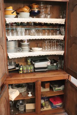 a wooden cabinet with many dishes and glasses on it