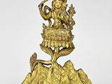 a gold statue of a woman sitting on top of a rock