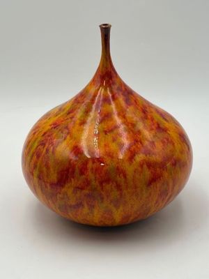 a red and yellow vase sitting on a white surface