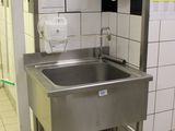 un lavabo dans des toilettes publiques, avec un distributeur de papier accroché au mur