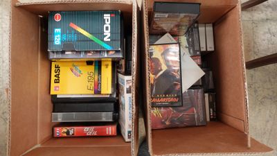 deux cartons remplis de DVD et de jeux posés par terre