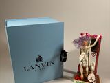 a figurine of a woman in a dress and hat next to a blue box