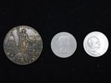 Trois pièces sont représentées sur une surface noire, sur fond noir.