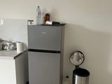 a small kitchen with a refrigerator, sink, and trash can