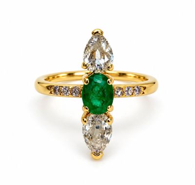 a close up of a ring with a green emerald and white diamonds