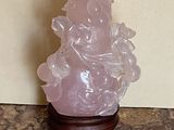 une statue en cristal rose posée sur une table en marbre