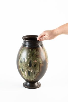 une main tendue vers un vase contenant une plante