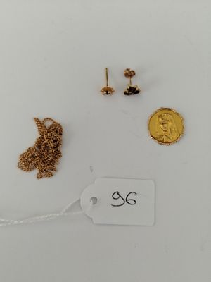 three pairs of earrings and a gold coin on a white surface