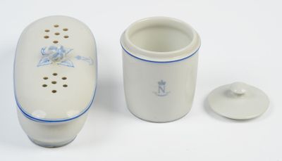 un vase blanc orné d'une fleur bleue, à côté d'une tasse
