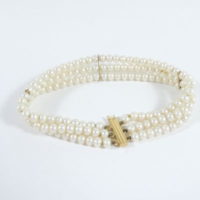 a close up of a white pearl bracelet with a gold clasp