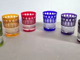 six verres de couleurs différentes sont alignés sur une table