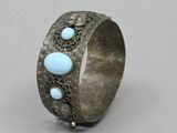 a close up of a silver bracelet with blue stones on it
