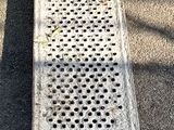 a long metal grate on the ground next to a building