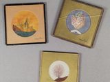 trois petites cartes ornées de peintures sont posées sur une table