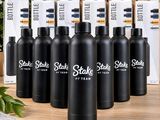 six gourdes en acier inoxydable noir posées sur une table en bois