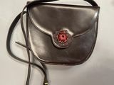 brown leather purse with flower decoration on strap on white surface