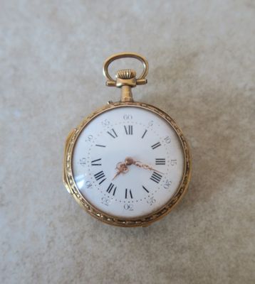 une petite montre de poche en or avec des chiffres romains