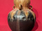 a black and gold vase sitting on a red surface