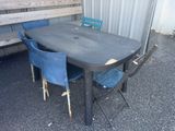 a table with four chairs and a bench in front of a building