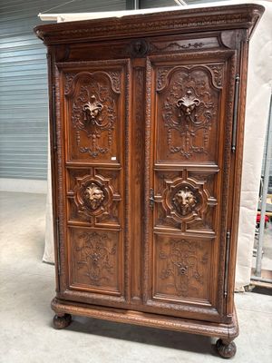 une armoire ancienne en bois avec des sculptures sur les portes
